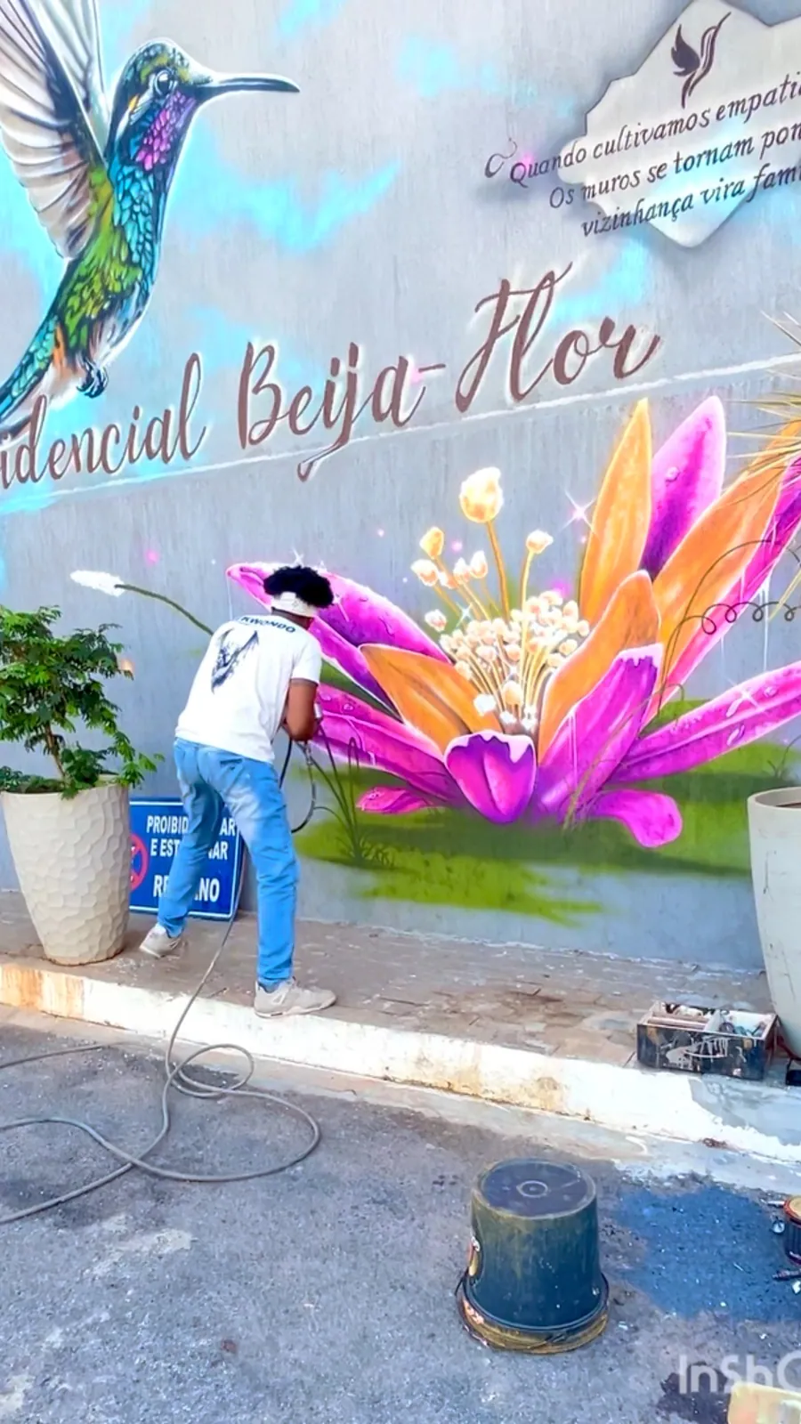 Fachada de condomínio com beija-flor e flores tropicais pintados em grande escala