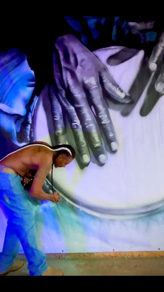 Mural de grande escala com mãos tocando berimbau em festival