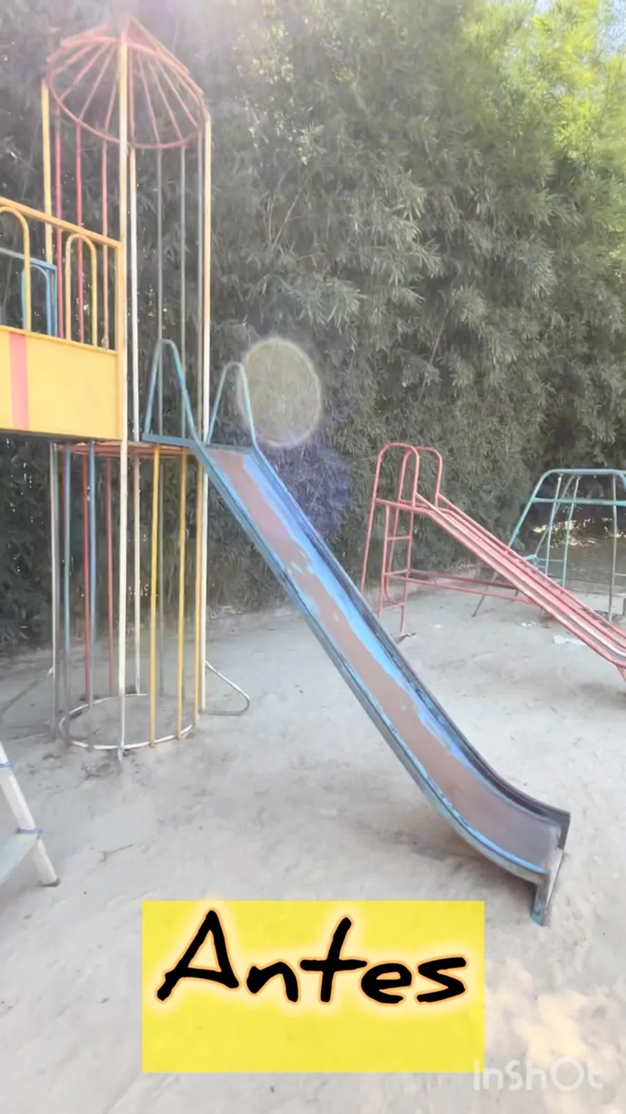 Playground de escola antes da intervenção, com estrutura metálica desbotada e sem cor