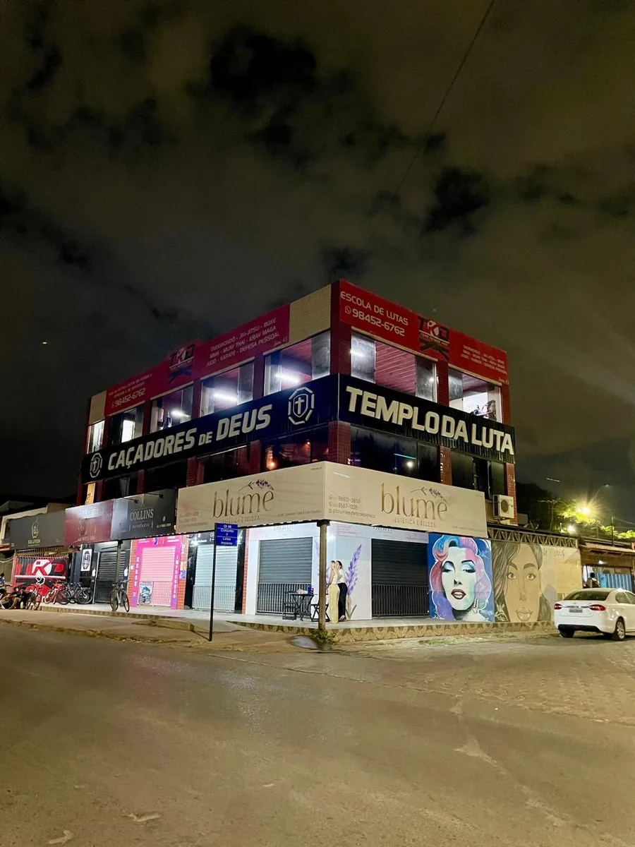 Prédio comercial de três pavimentos com fachada padronizada, letra caixa iluminada e sinalização das lojas, em Brasília